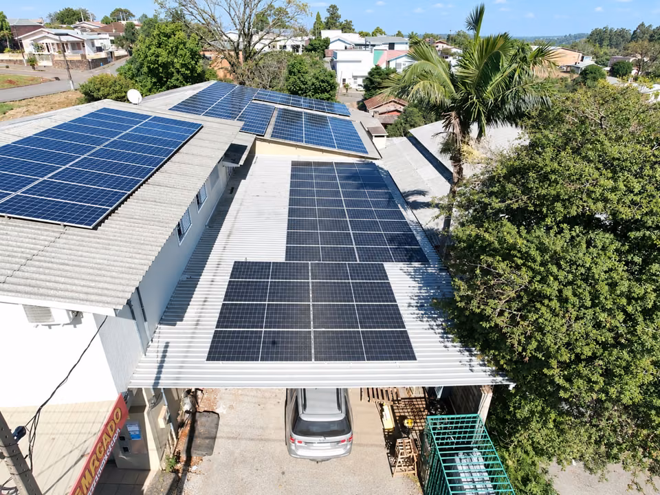 Vista aérea de residência com módulos solares distribuídos sobre o telhado, em Belmonte.