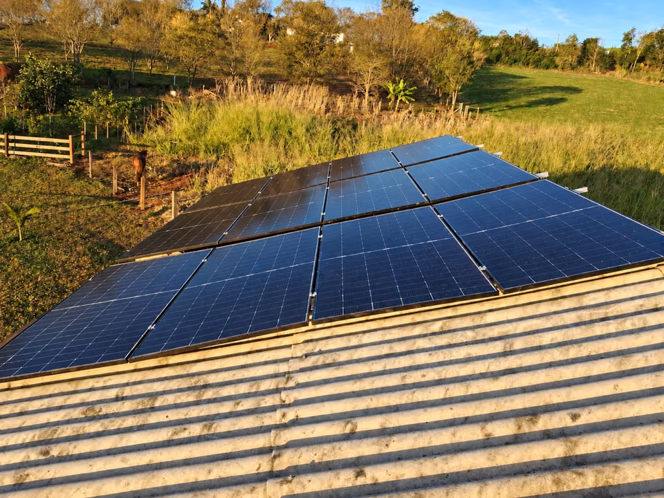 Conjunto de módulos solares sobre telhado em paisagem rural, em Descanso.