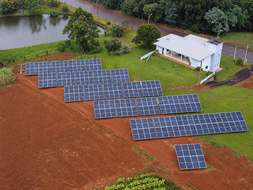 Vista aérea de usina solar no solo ao lado de uma casa branca, em Iporã do Oeste.
