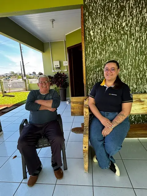Cliente e representante da Global Solar na varanda de uma residência, com o inversor instalado ao fundo